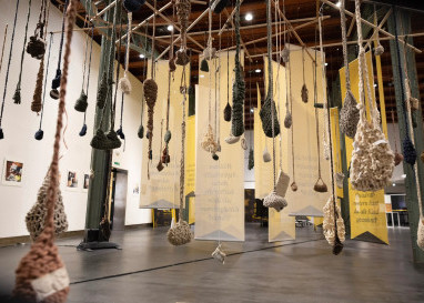 Das Häkeln von Taschen gibt mexikanischen Frauen einen Zugang zu ihrer Erfahrung einer der Sterilisation – und die Fragen auf Stoffbahnen empfangen Ausstellungsbesuchende einnehmend. (Foto: Thomas Batschelet)